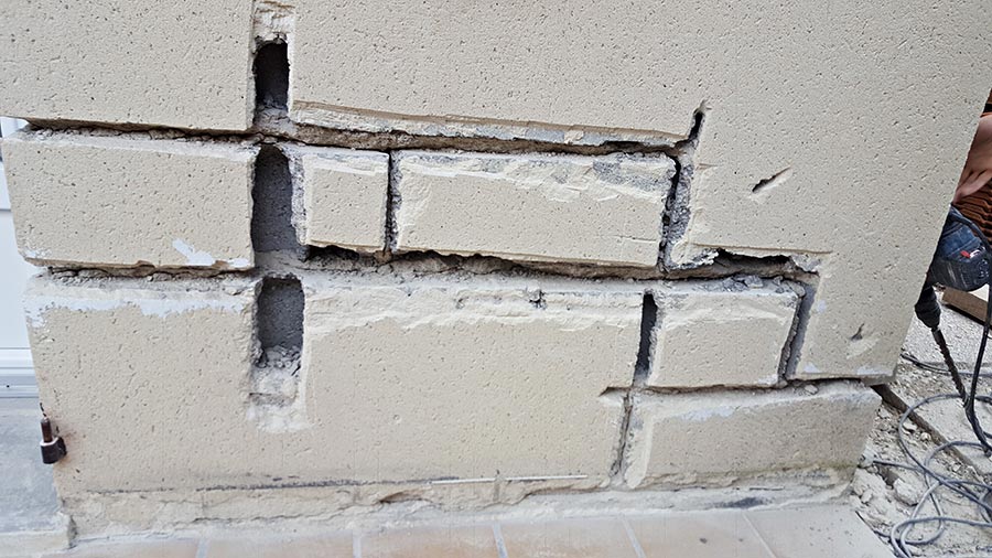 Mur en briques avec trous et fissures.