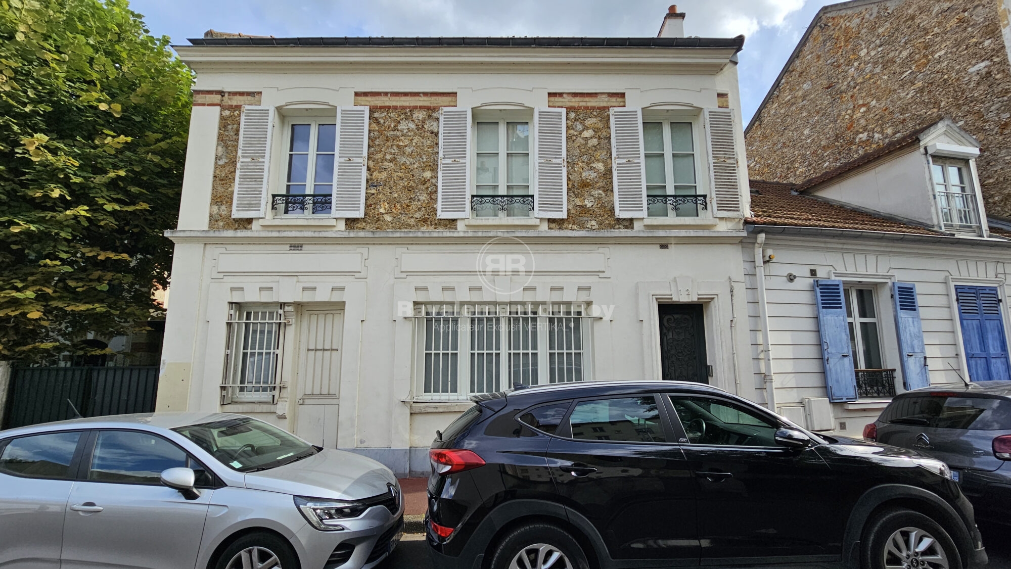 Façade de maison avec volets fermés et véhicules devant