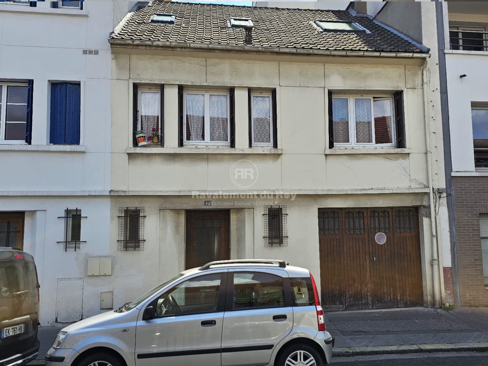 Façade d'une maison ancienne avec voiture garée devant.