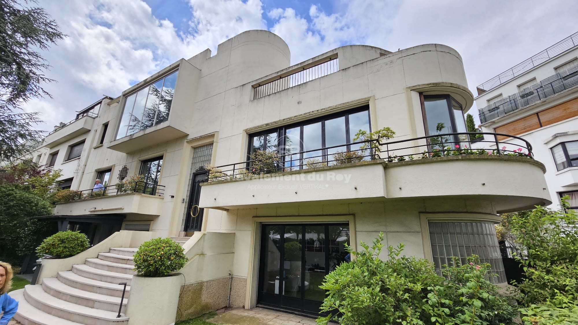 Grande maison moderne avec balcons et escaliers.