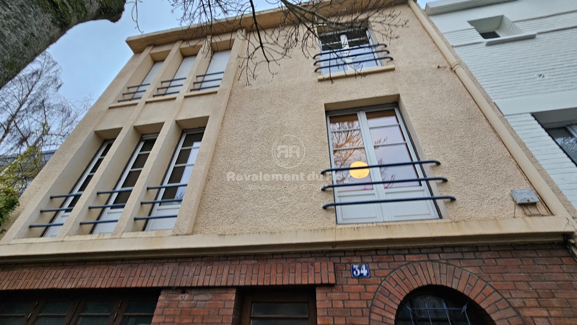 Façade de bâtiment en ravalement avec balcons en métal et brique apparente